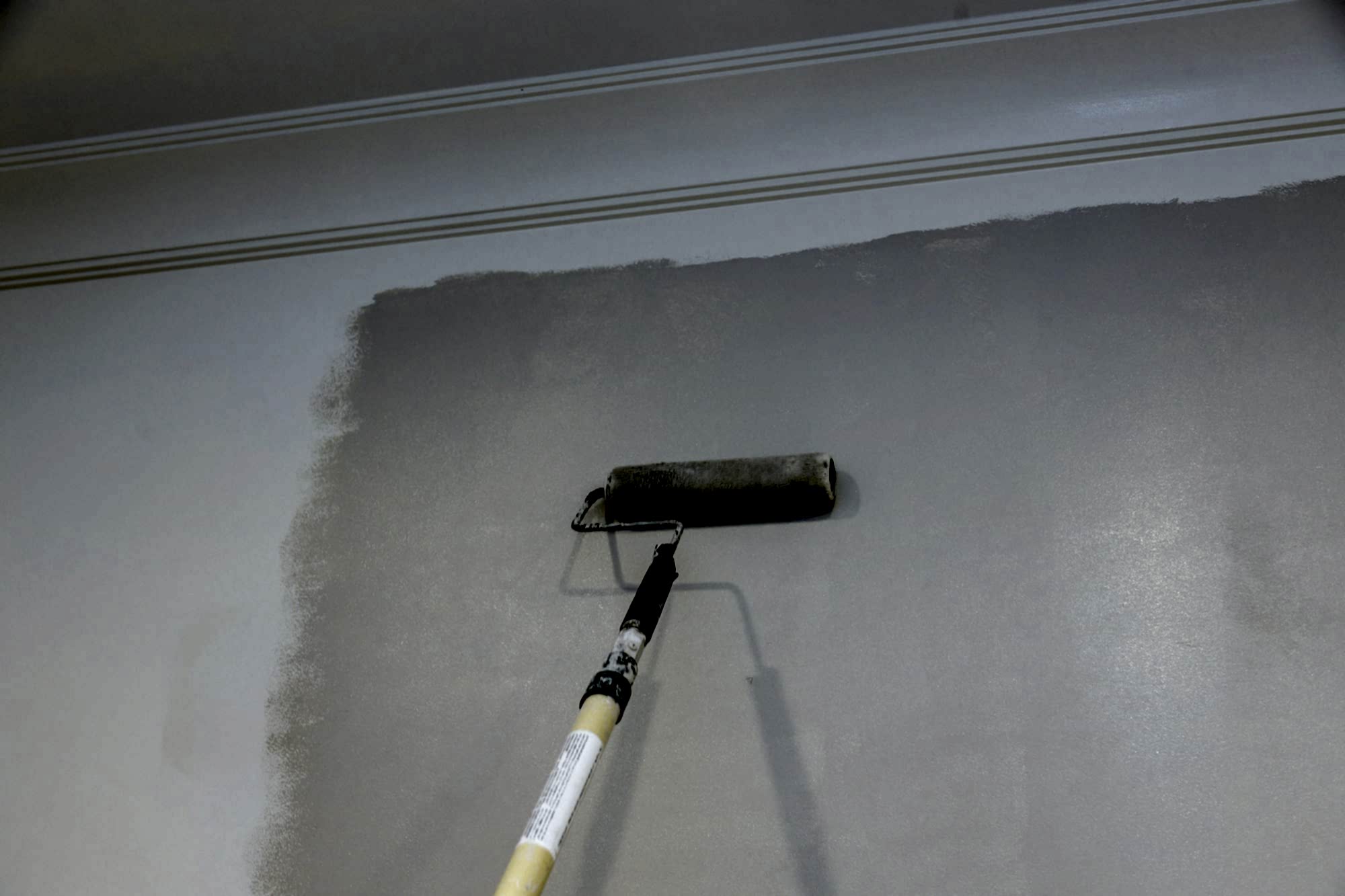 Male hand painting wall with paint roller painting apartment, renovating with color paint